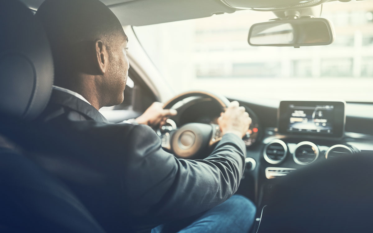 Young African man driving a car through the city saving on car insurance.jpg