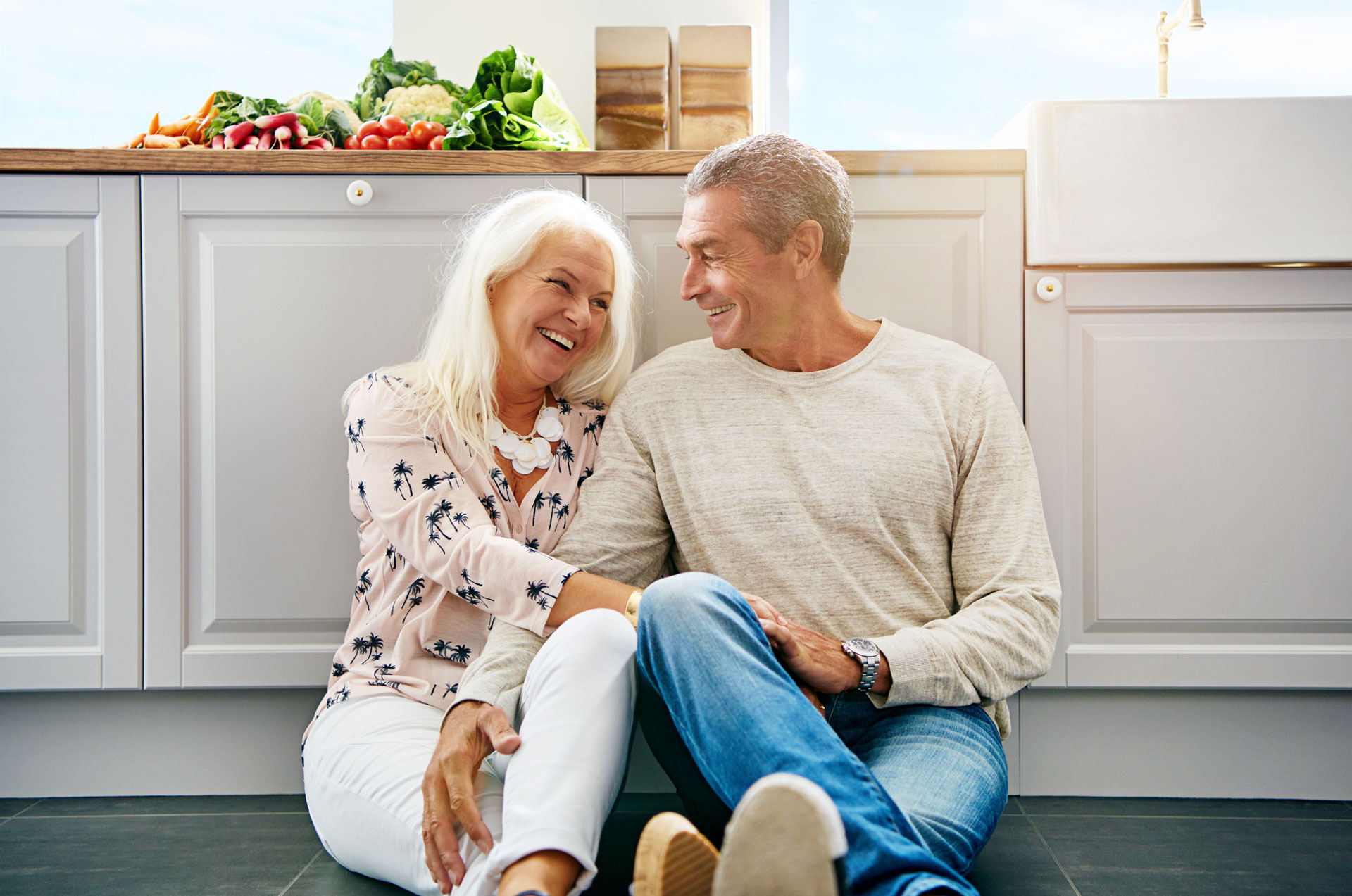 elderly couple chatting about life insurance on a kitchen floor